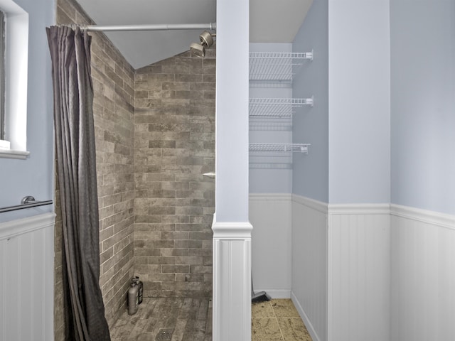 bathroom featuring a wainscoted wall and a tile shower