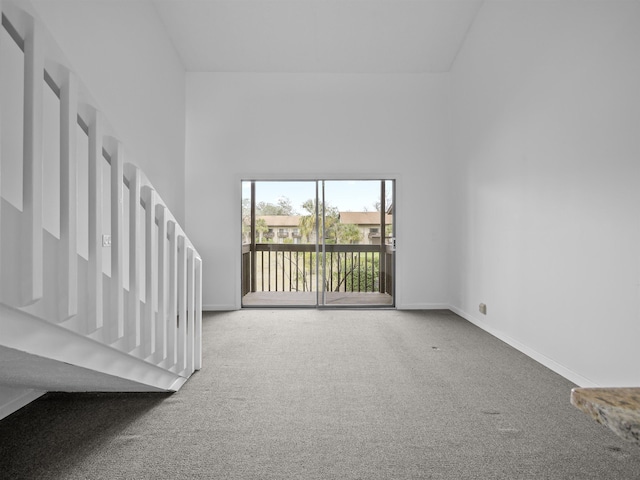 interior space with carpet floors, a towering ceiling, and baseboards