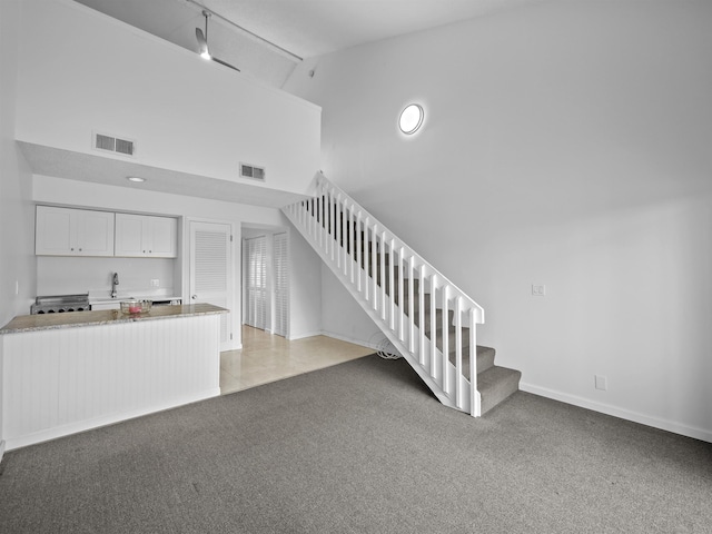 staircase featuring high vaulted ceiling, carpet, visible vents, and baseboards