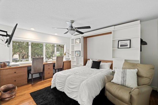 bedroom with ceiling fan, light hardwood / wood-style flooring, and a textured ceiling