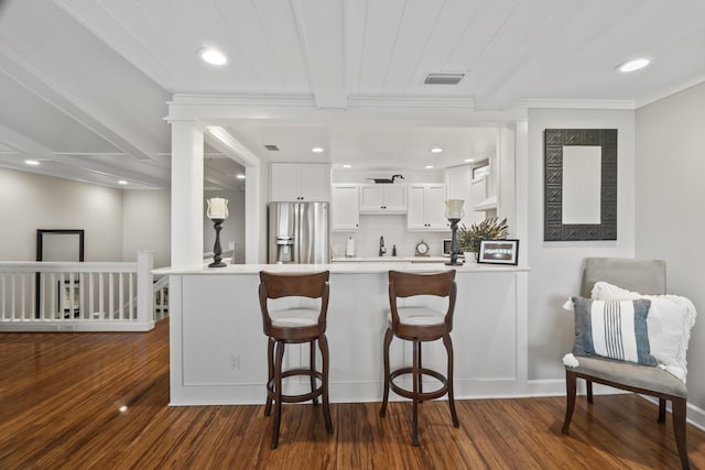 kitchen featuring white cabinets, stainless steel fridge, dark hardwood / wood-style flooring, and kitchen peninsula