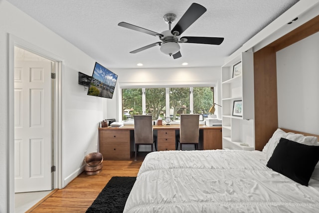 bedroom with ceiling fan, light hardwood / wood-style floors, and a textured ceiling