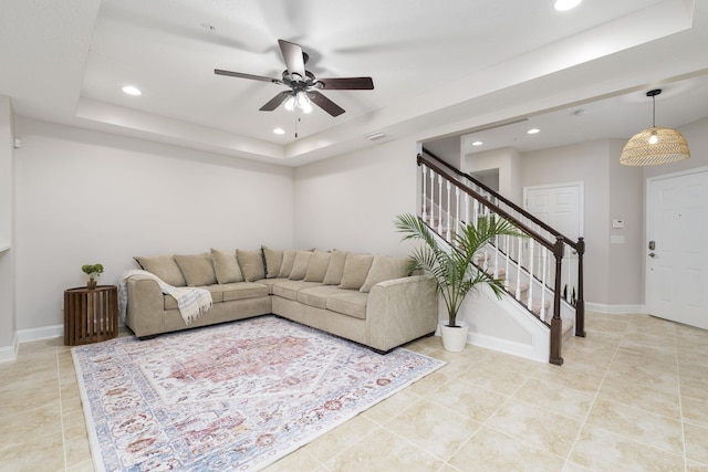 tiled living room featuring ceiling fan and a tray ceiling