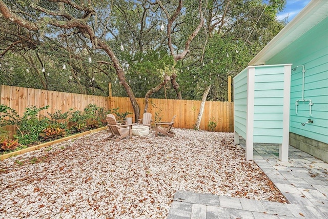 view of yard featuring a fenced backyard, a fire pit, and a patio