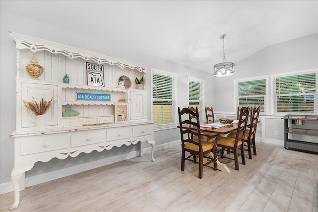 dining space with vaulted ceiling, light wood-style flooring, and an inviting chandelier