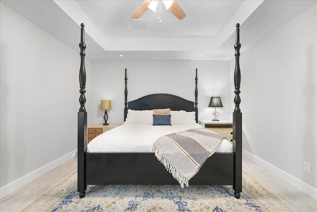 bedroom featuring a raised ceiling, visible vents, and baseboards