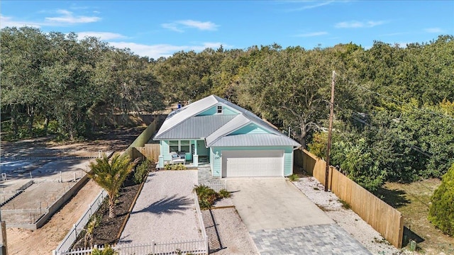 view of front of home featuring a fenced front yard, a porch, an attached garage, metal roof, and driveway