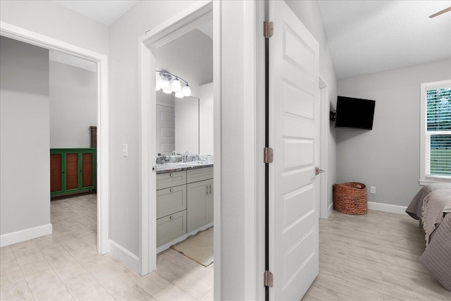 ensuite bathroom featuring ensuite bathroom, wood finished floors, vanity, and baseboards