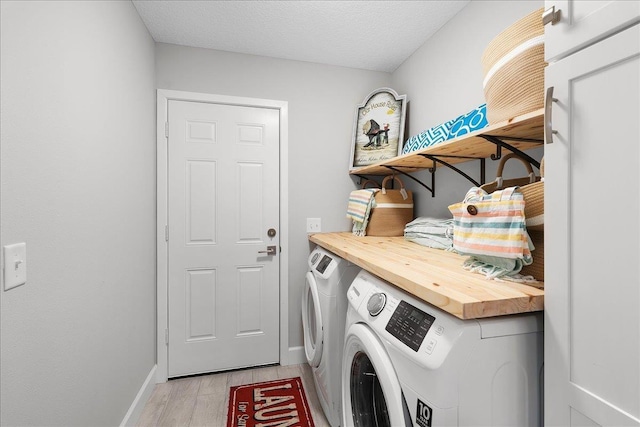 laundry room with a textured ceiling, separate washer and dryer, light wood-type flooring, laundry area, and baseboards