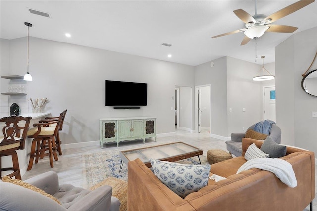 living area featuring light wood-type flooring, visible vents, ceiling fan, and baseboards