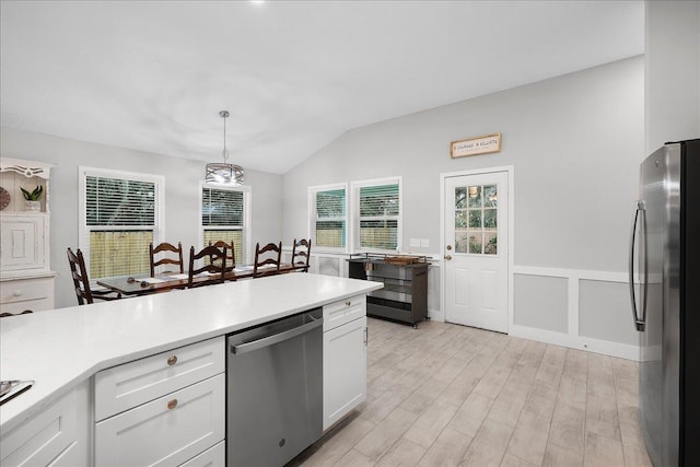 kitchen featuring stainless steel appliances, white cabinetry, vaulted ceiling, light countertops, and pendant lighting