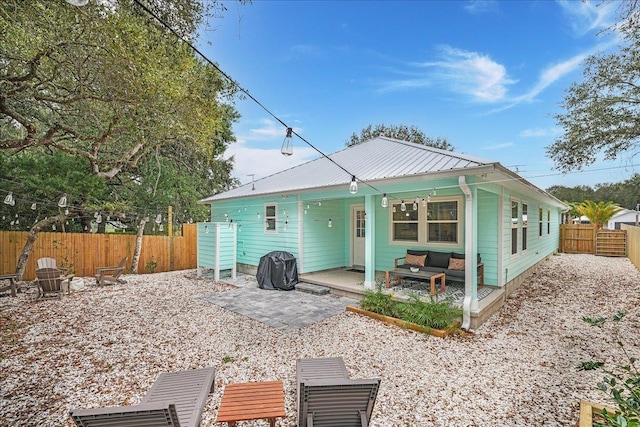 back of property featuring metal roof, a patio, an outdoor hangout area, and a fenced backyard