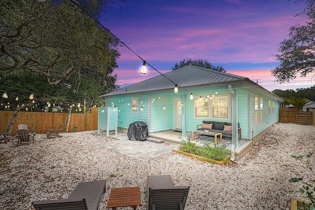 back of house at dusk with a patio area, a fenced backyard, an outdoor hangout area, and metal roof