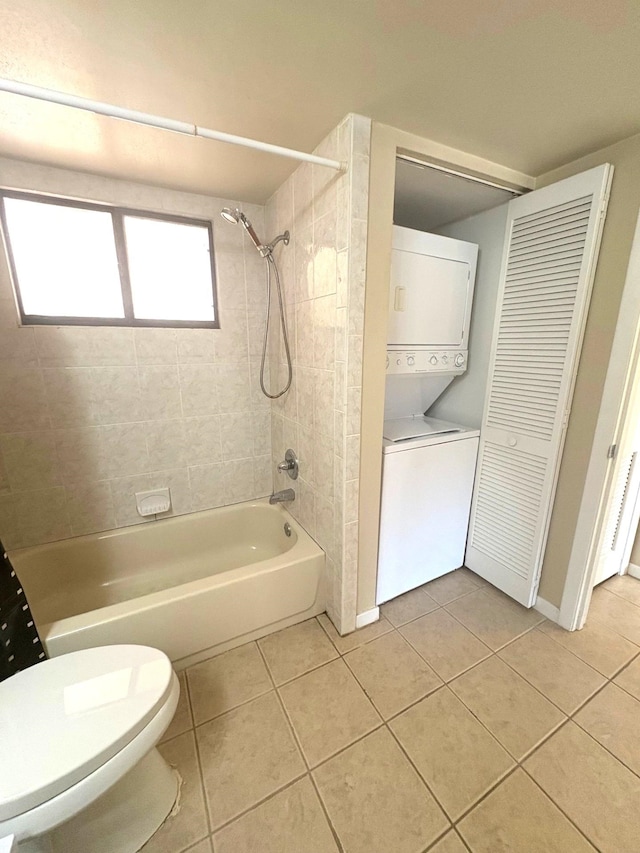 bathroom featuring toilet, washtub / shower combination, stacked washer and dryer, and tile patterned floors