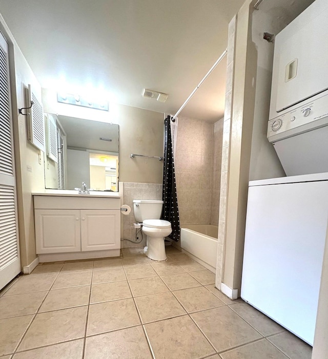 bathroom with shower / tub combo with curtain, toilet, stacked washer and dryer, and tile patterned floors