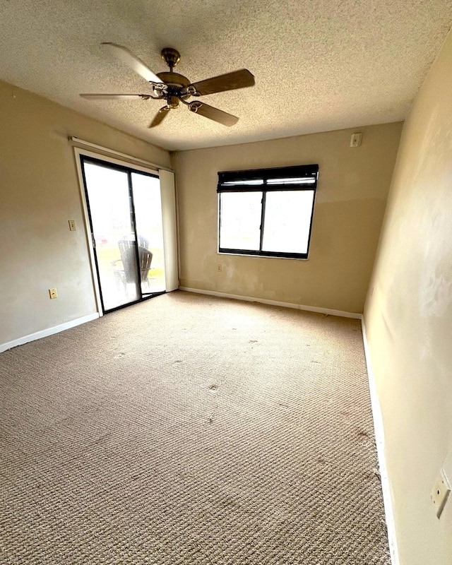 spare room featuring a textured ceiling, light carpet, baseboards, and a ceiling fan