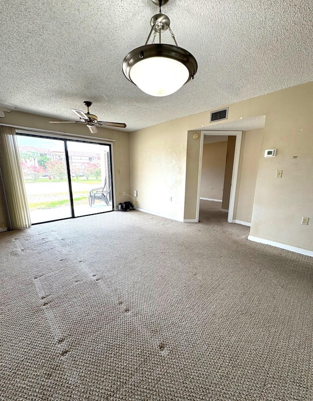 carpeted spare room with a textured ceiling, visible vents, baseboards, and ceiling fan