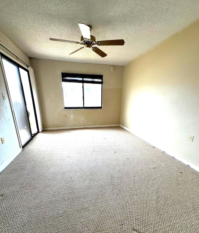 carpeted spare room featuring baseboards, a healthy amount of sunlight, and ceiling fan