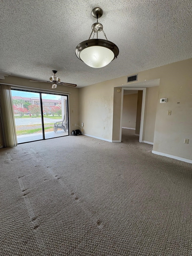 spare room featuring a textured ceiling, baseboards, ceiling fan, visible vents, and light colored carpet