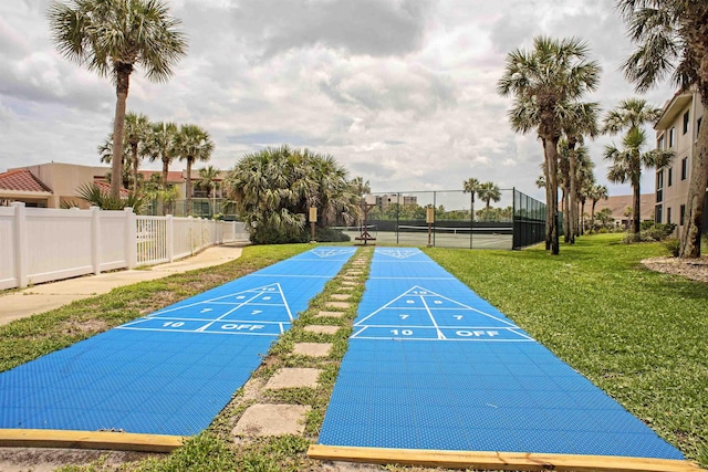 view of property's community with fence, shuffleboard, and a lawn