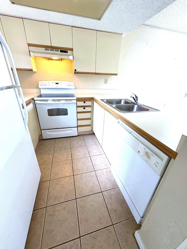 kitchen with under cabinet range hood, light tile patterned floors, white appliances, a sink, and light countertops