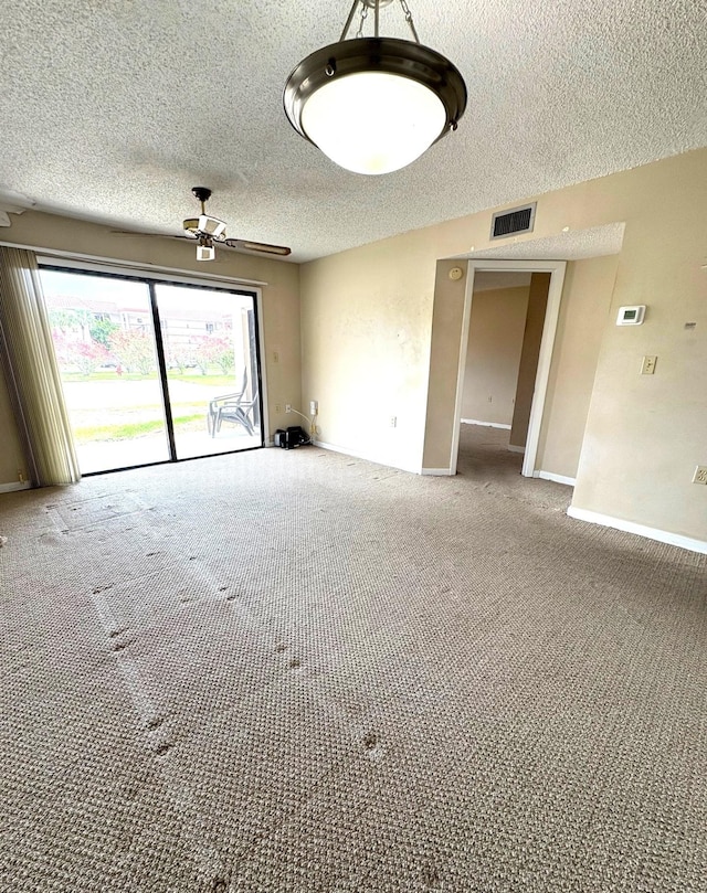 unfurnished room featuring a textured ceiling, carpet, visible vents, a ceiling fan, and baseboards