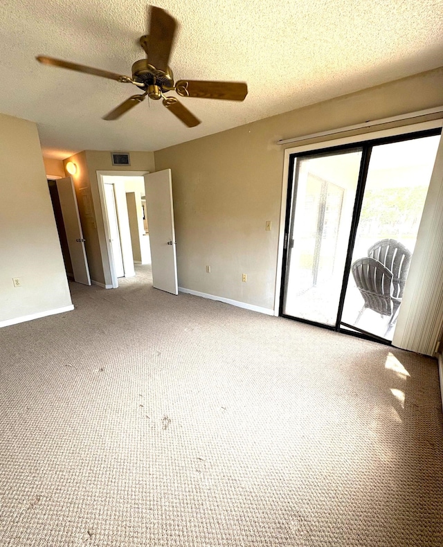 empty room with a ceiling fan, carpet floors, a textured ceiling, visible vents, and baseboards