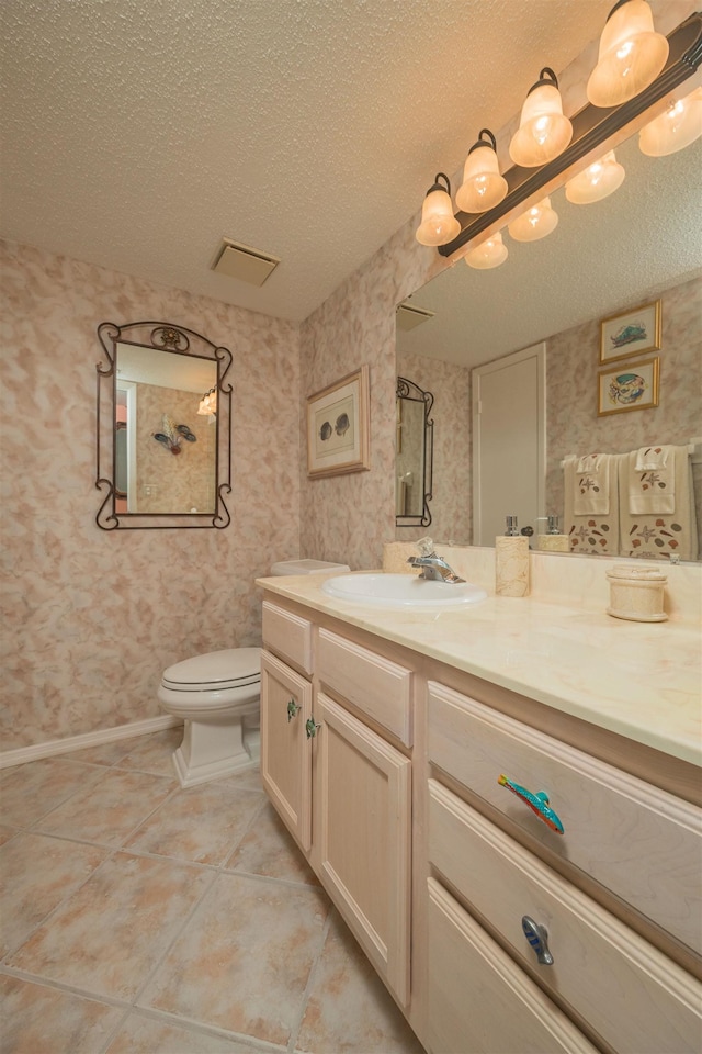 bathroom featuring tile patterned flooring, vanity, a textured ceiling, and toilet