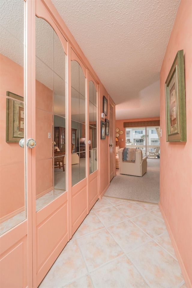 hallway featuring light tile patterned floors, a textured ceiling, and french doors