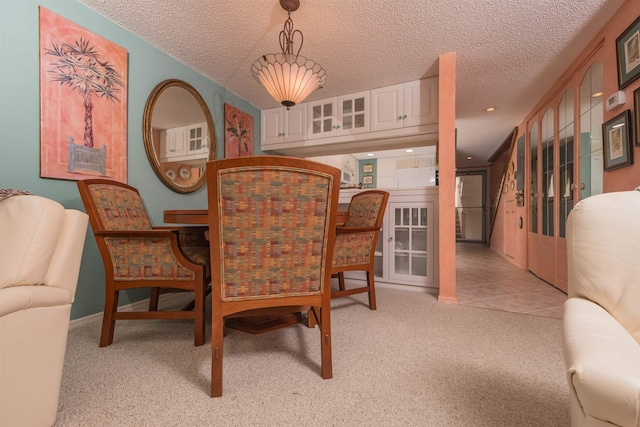 dining area with light colored carpet and a textured ceiling