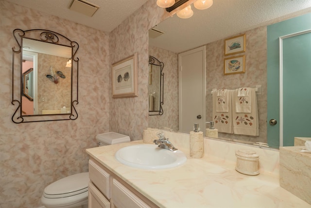 bathroom with vanity, toilet, and a textured ceiling