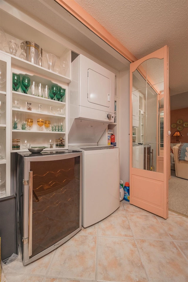 washroom with a textured ceiling, light tile patterned flooring, and stacked washer and clothes dryer