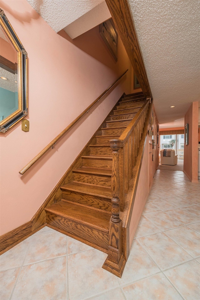 staircase featuring tile patterned flooring and a textured ceiling