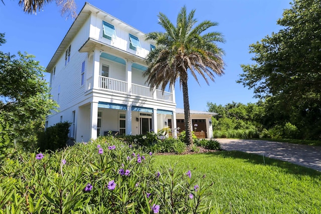 view of front of house featuring a balcony, a front yard, and a garage