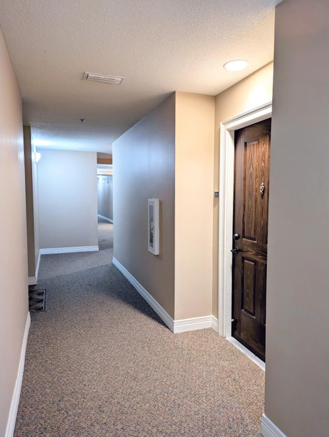 hallway featuring carpet floors and a textured ceiling