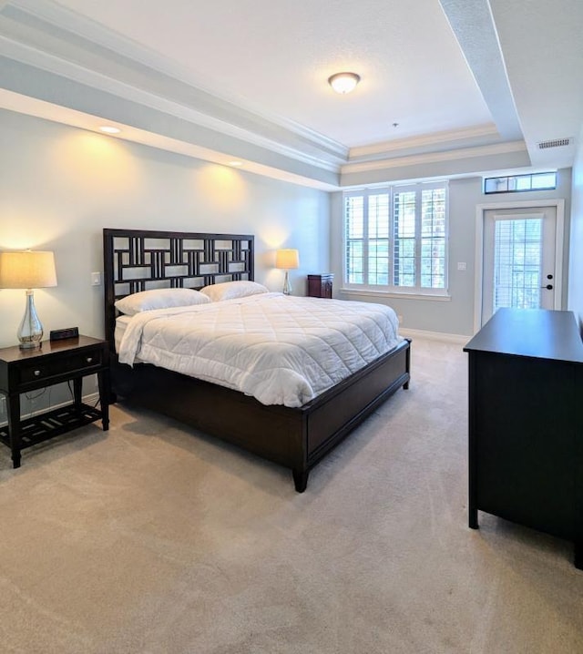 carpeted bedroom with a tray ceiling and crown molding