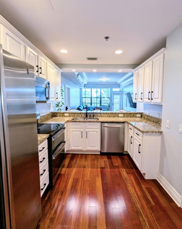 kitchen with white cabinets, dark hardwood / wood-style flooring, kitchen peninsula, and stainless steel appliances