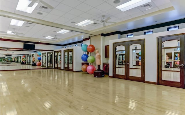 exercise area featuring french doors, light wood-type flooring, and a paneled ceiling