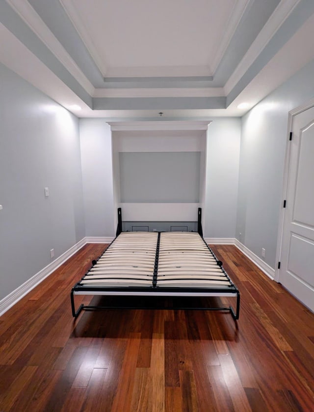 bedroom with a raised ceiling, crown molding, and dark wood-type flooring