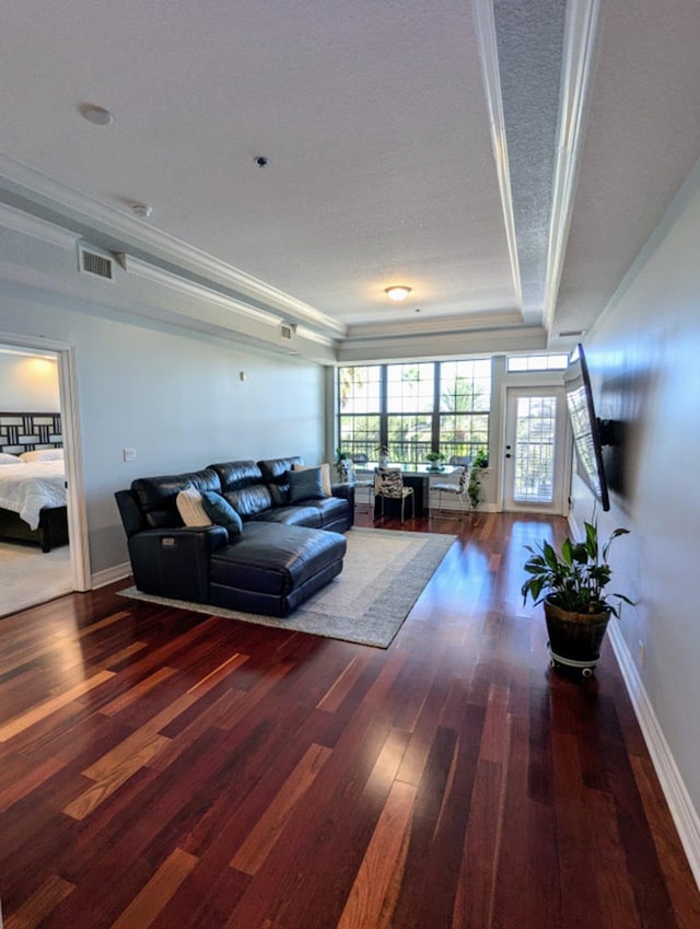 living room featuring dark hardwood / wood-style flooring, a textured ceiling, and ornamental molding