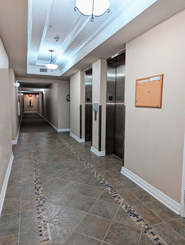 corridor with a tray ceiling, elevator, and ornamental molding