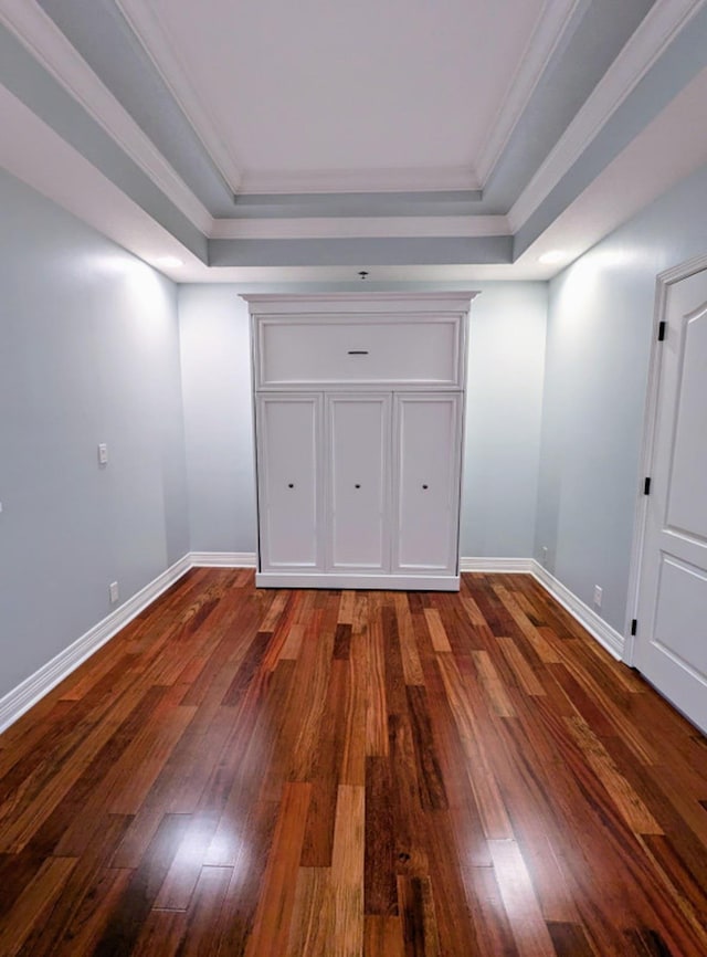 interior space with a tray ceiling, crown molding, and dark hardwood / wood-style flooring