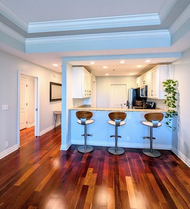 kitchen with a kitchen bar, kitchen peninsula, white cabinetry, and appliances with stainless steel finishes