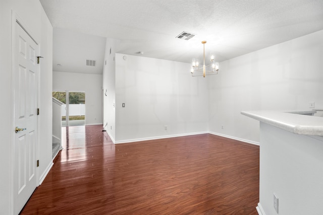 unfurnished dining area featuring a chandelier, visible vents, baseboards, and wood finished floors