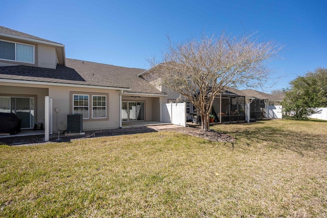 rear view of property with a lawn, cooling unit, and fence