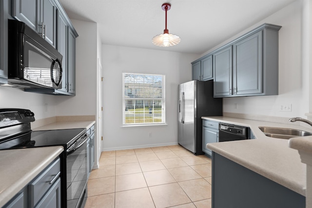 kitchen featuring light tile patterned flooring, a sink, black appliances, light countertops, and pendant lighting