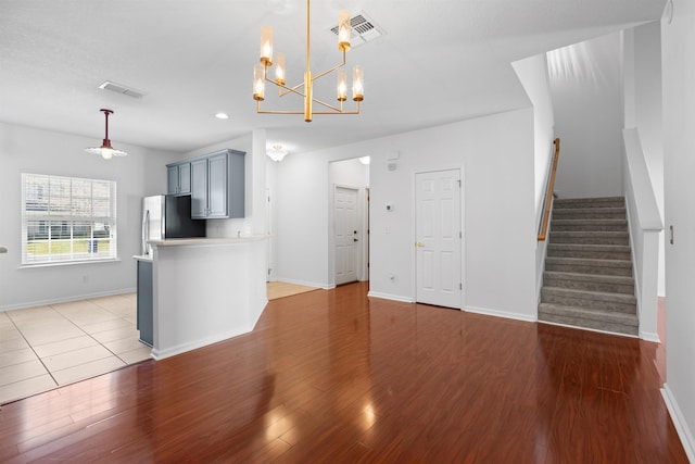 unfurnished living room with visible vents, light wood-style flooring, and stairs