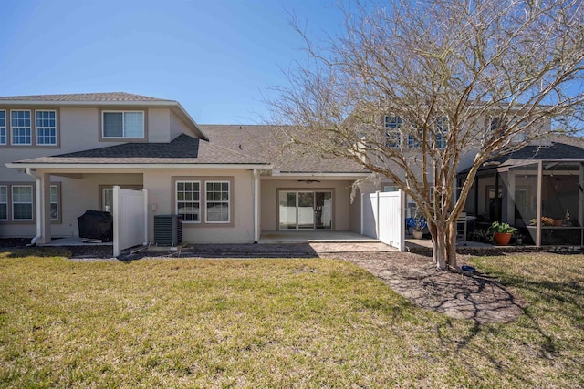 back of property with central air condition unit, roof with shingles, stucco siding, a lawn, and a patio area