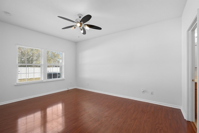 spare room with ceiling fan, baseboards, and dark wood finished floors