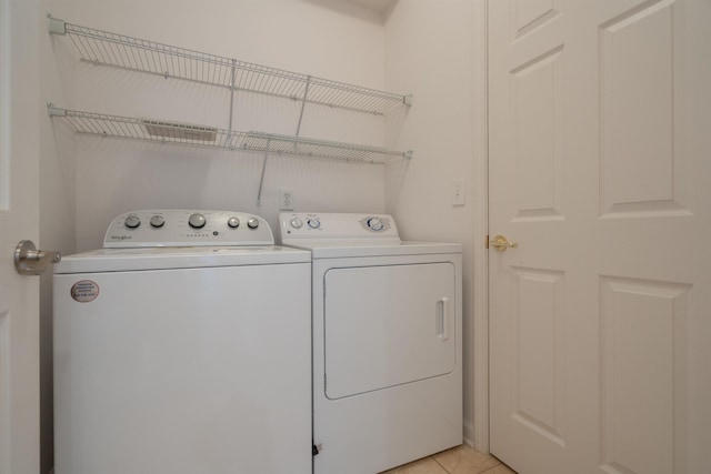 laundry room featuring light tile patterned floors, laundry area, and separate washer and dryer